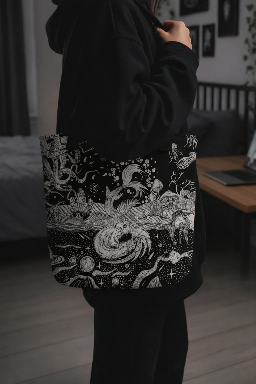 Person holding a tote bag with a black and white design in a room.