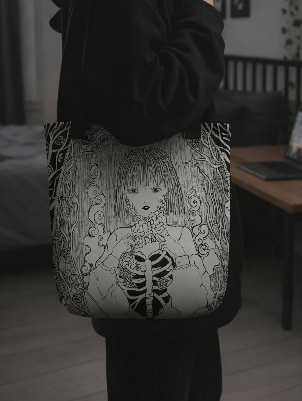 Person holding a tote bag with a black and white illustration of a skeleton girl.