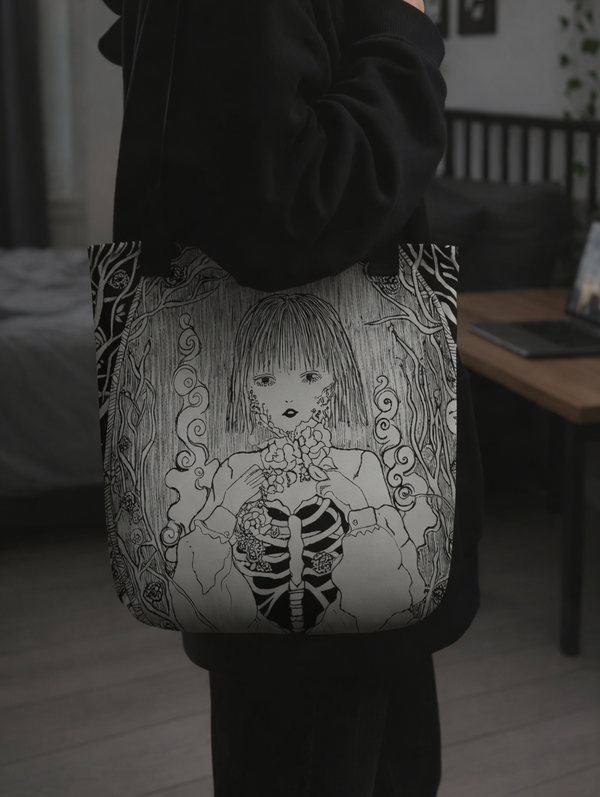 Person holding a tote bag with a black and white illustration of a skeleton girl.